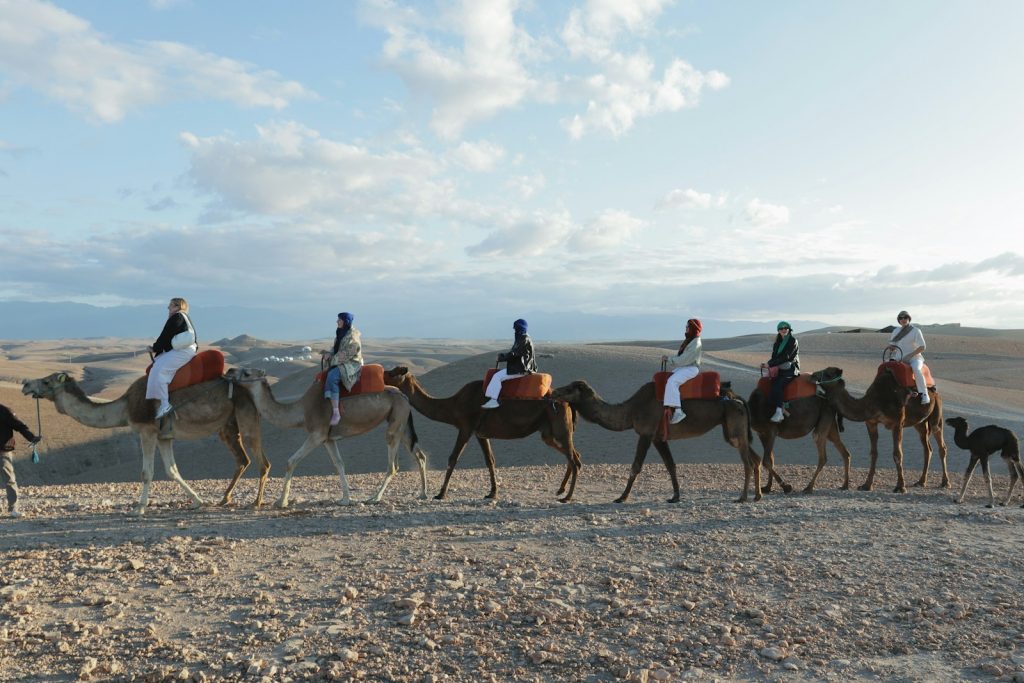 People are riding camels through the desert.