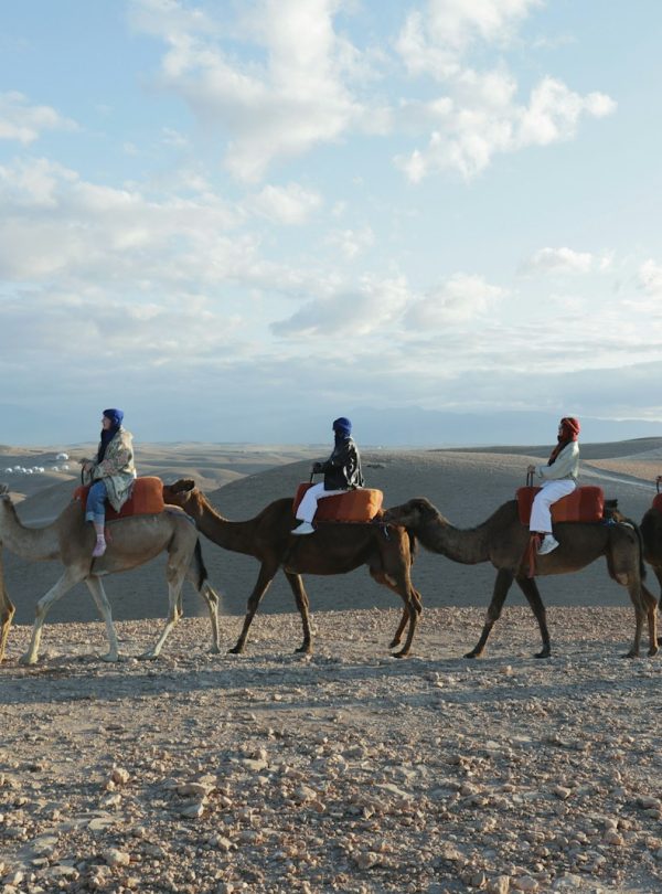 People are riding camels through the desert.