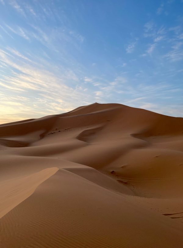 a large sand dune with a blue sky in the background