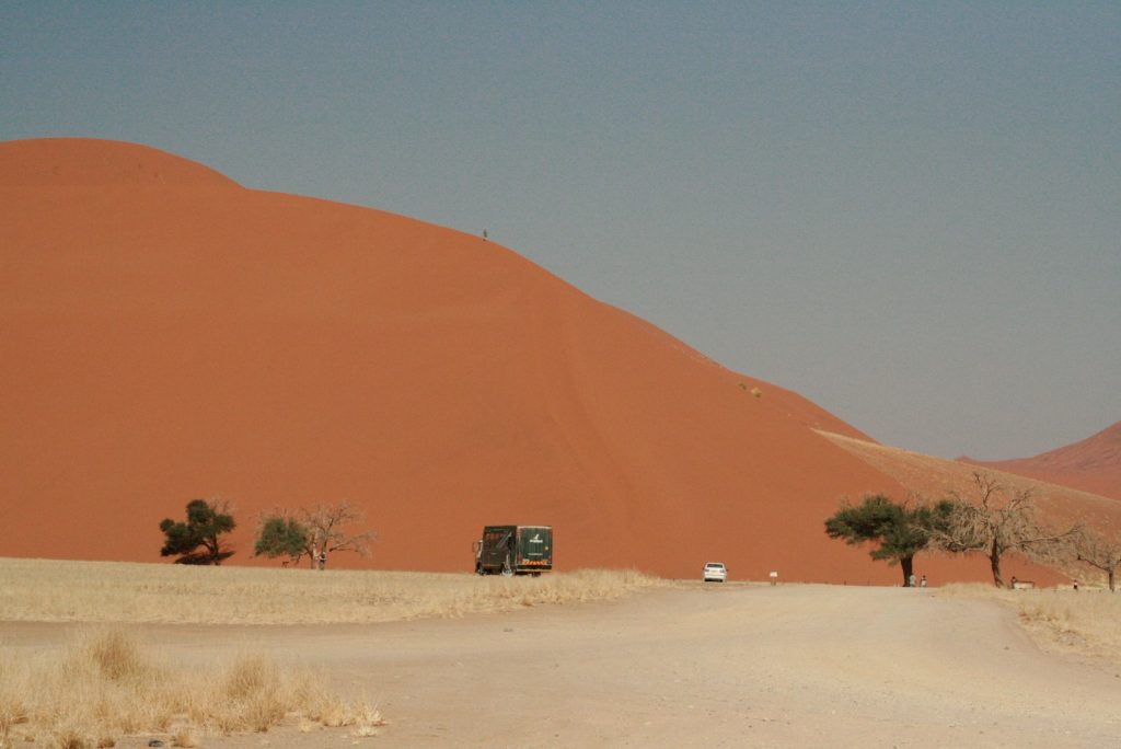 a truck driving down a dirt road in the desert