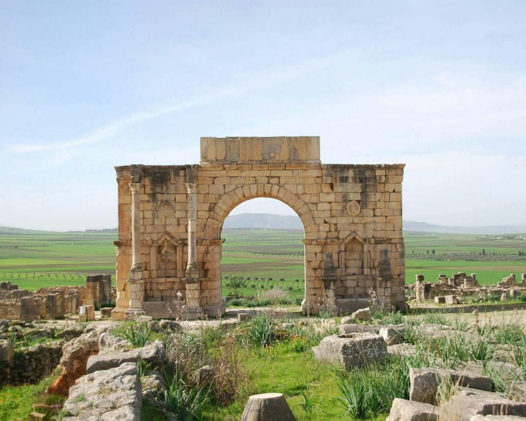 A stone arch in the middle of a field