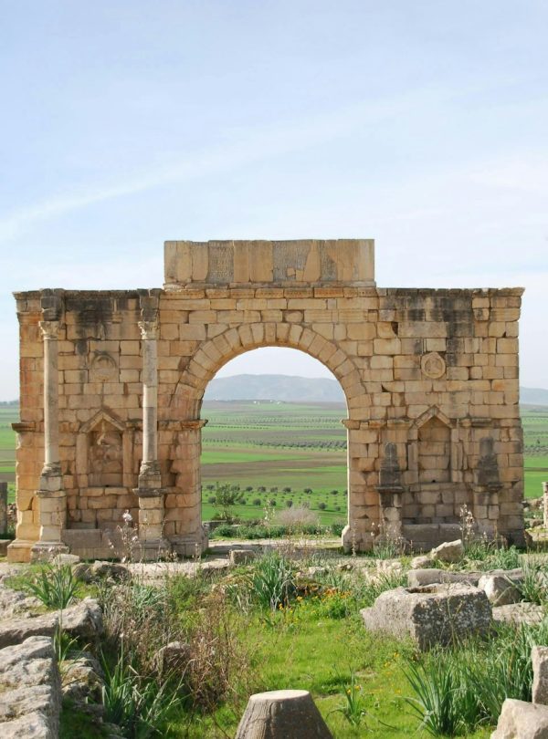 A stone arch in the middle of a field