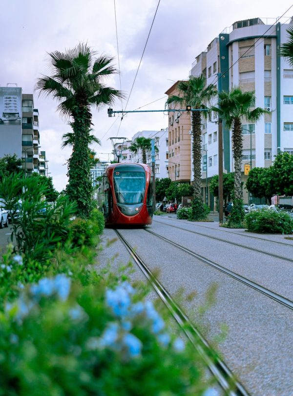 A red train traveling down train tracks next to tall buildings