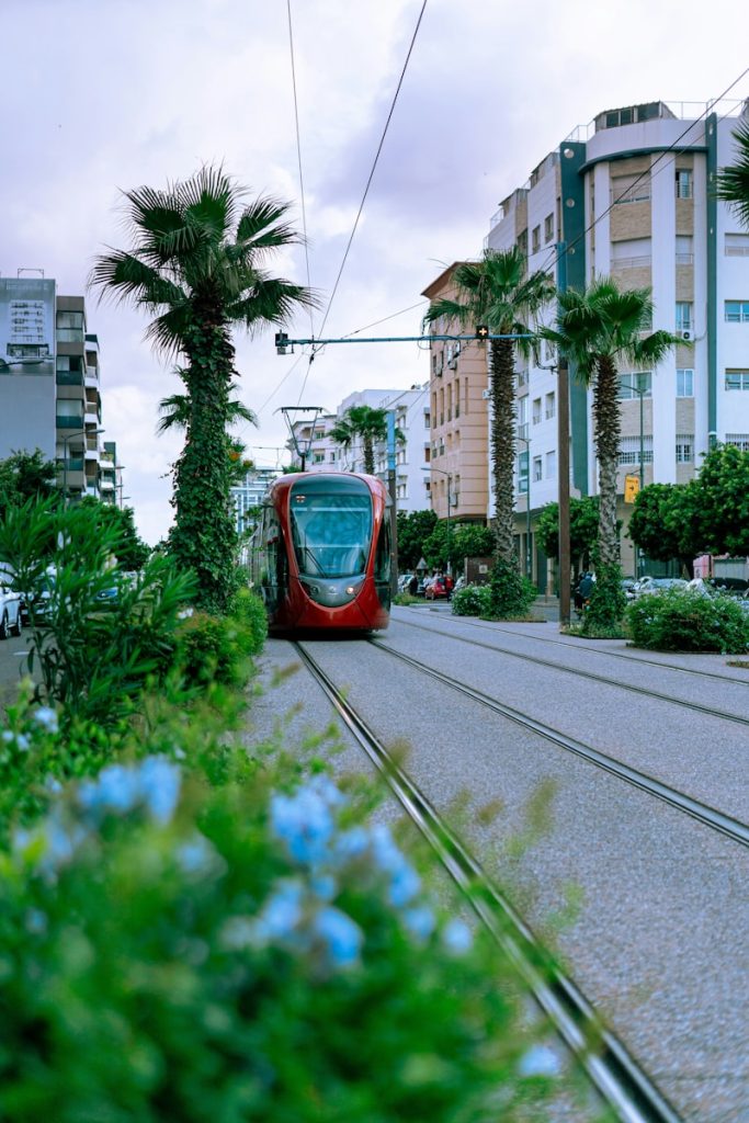 A red train traveling down train tracks next to tall buildings