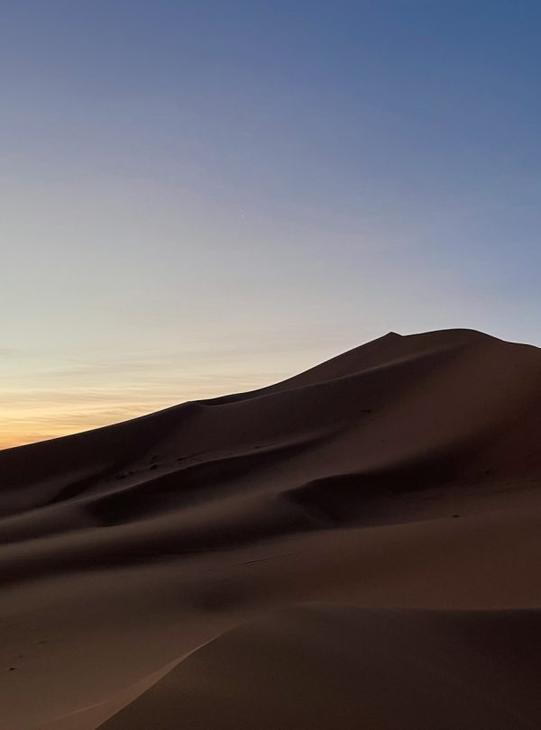 the sun is setting over the sand dunes