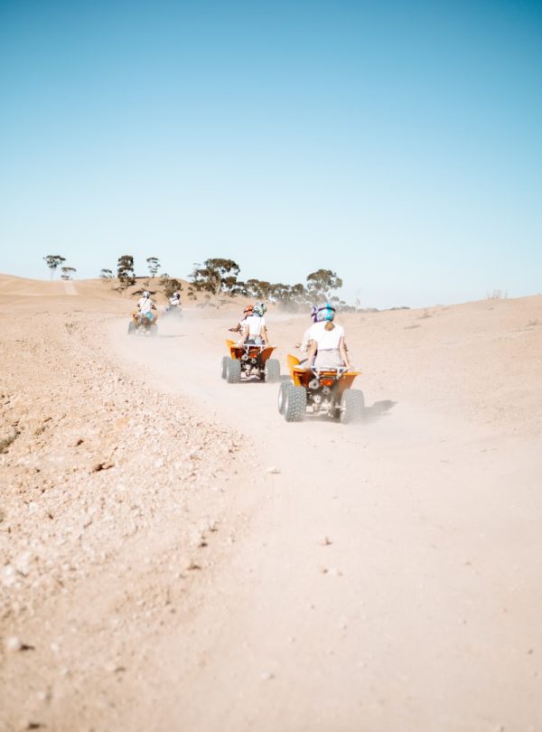 people riding motorcycle on brown sand during daytime